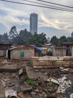 A slum consisting of cheaply built, small homes under demolition in Addis Ababa, Ethiopia, again with a tower in the background.