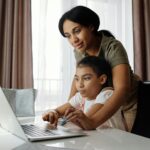 Mother Helping her Daughter use a Laptop