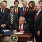 President Trump and a group surround a desk