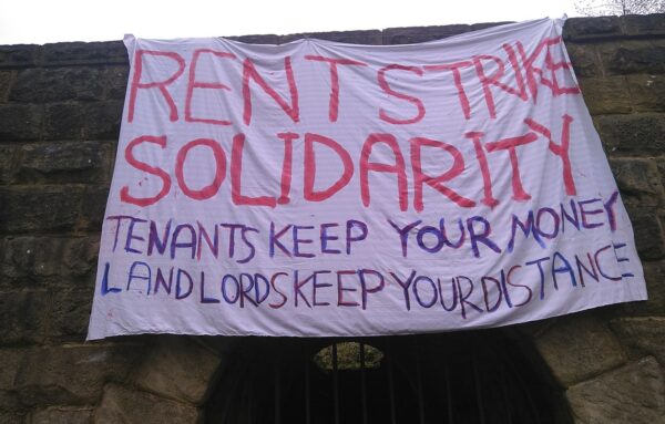 A sign calling for a rent strike hanging off a building.